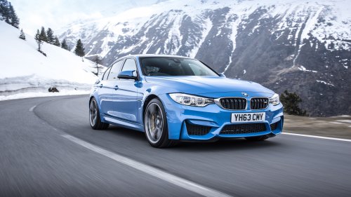 Синий BMW M3 едет по дороге вдоль снежных гор