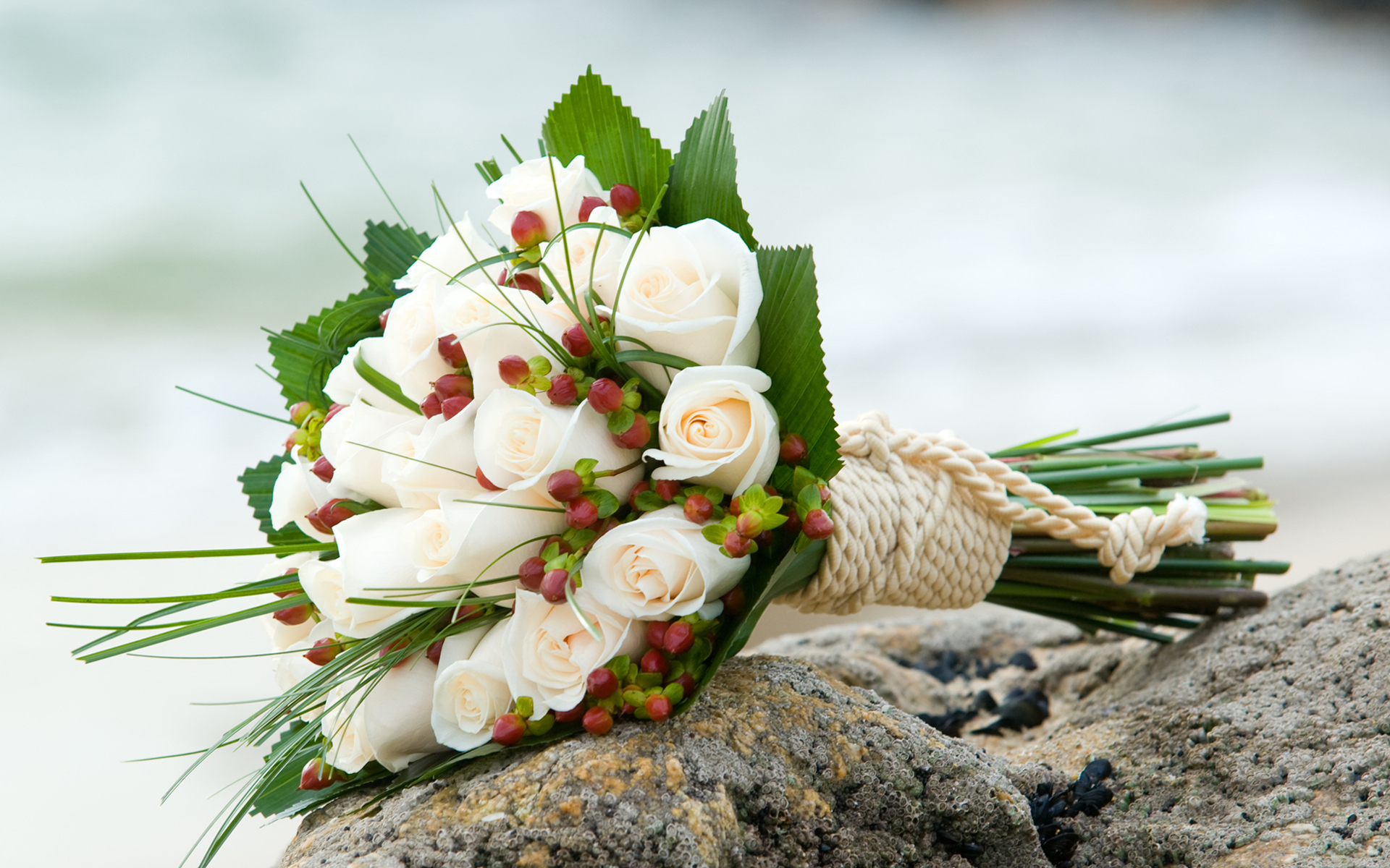 Букет невесты из белых роз перевязанный белой веревкой лежит на камне