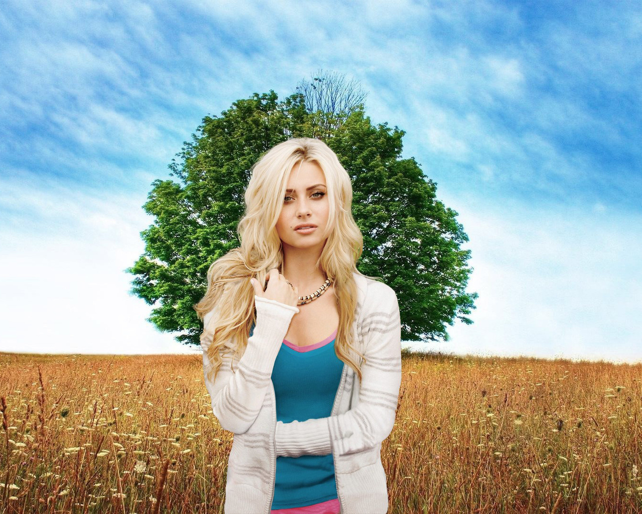 Девушка стоит в поле на фоне дерева и голубого неба