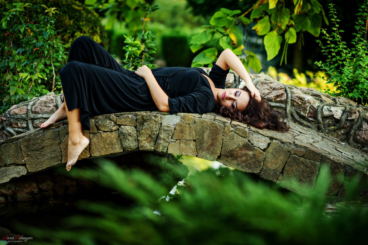 Девушка в черном платье лежит на каменном мосту, фотограф Анна Асланян