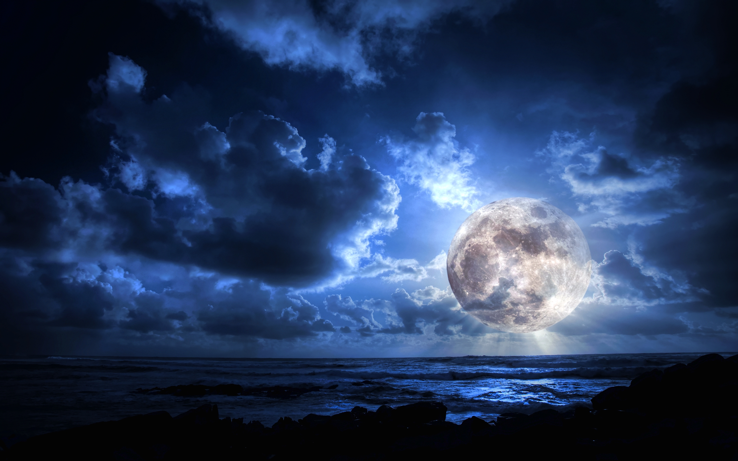 Луна, окруженная тучами, возвышается над морем