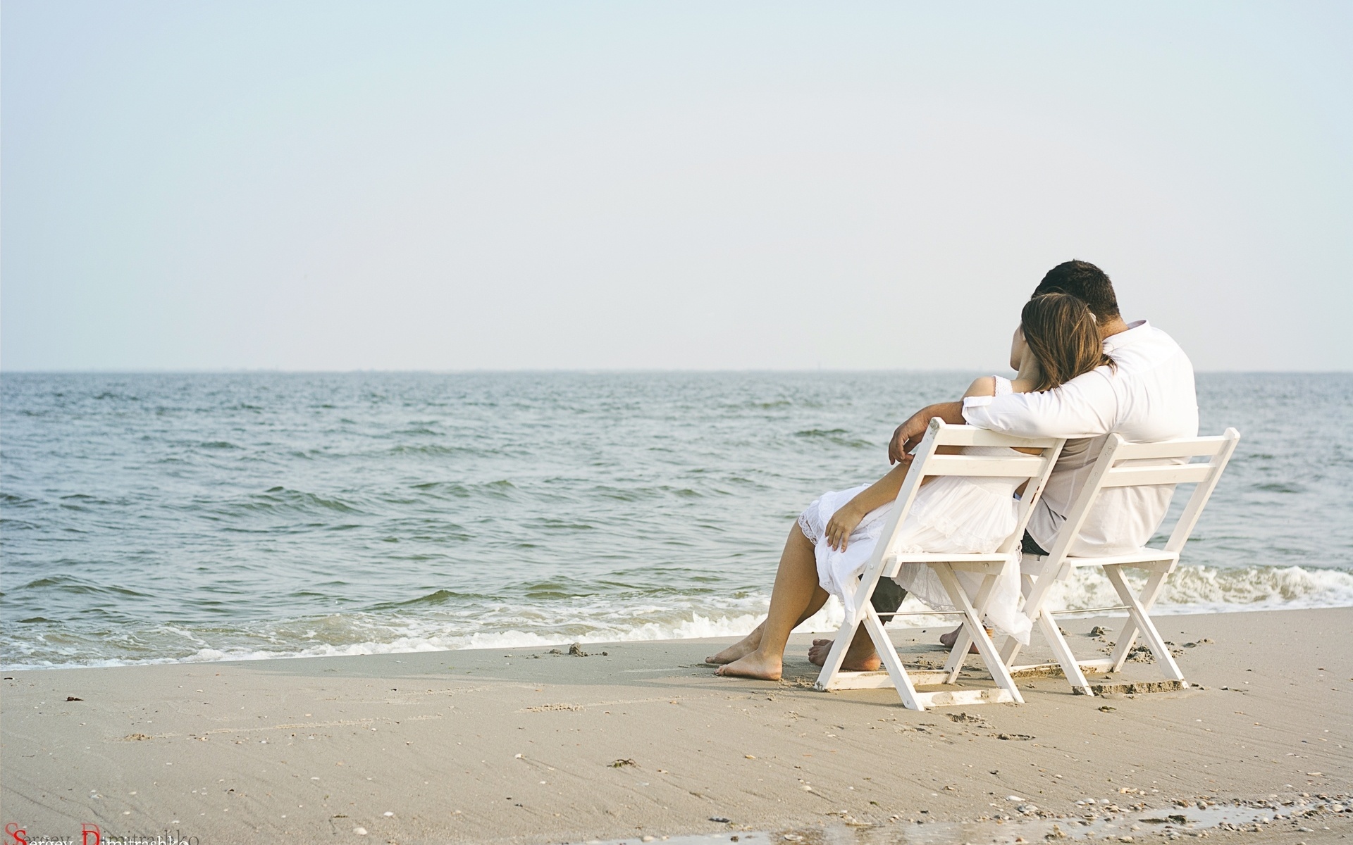 Парень и девушка сидят на стульях у моря