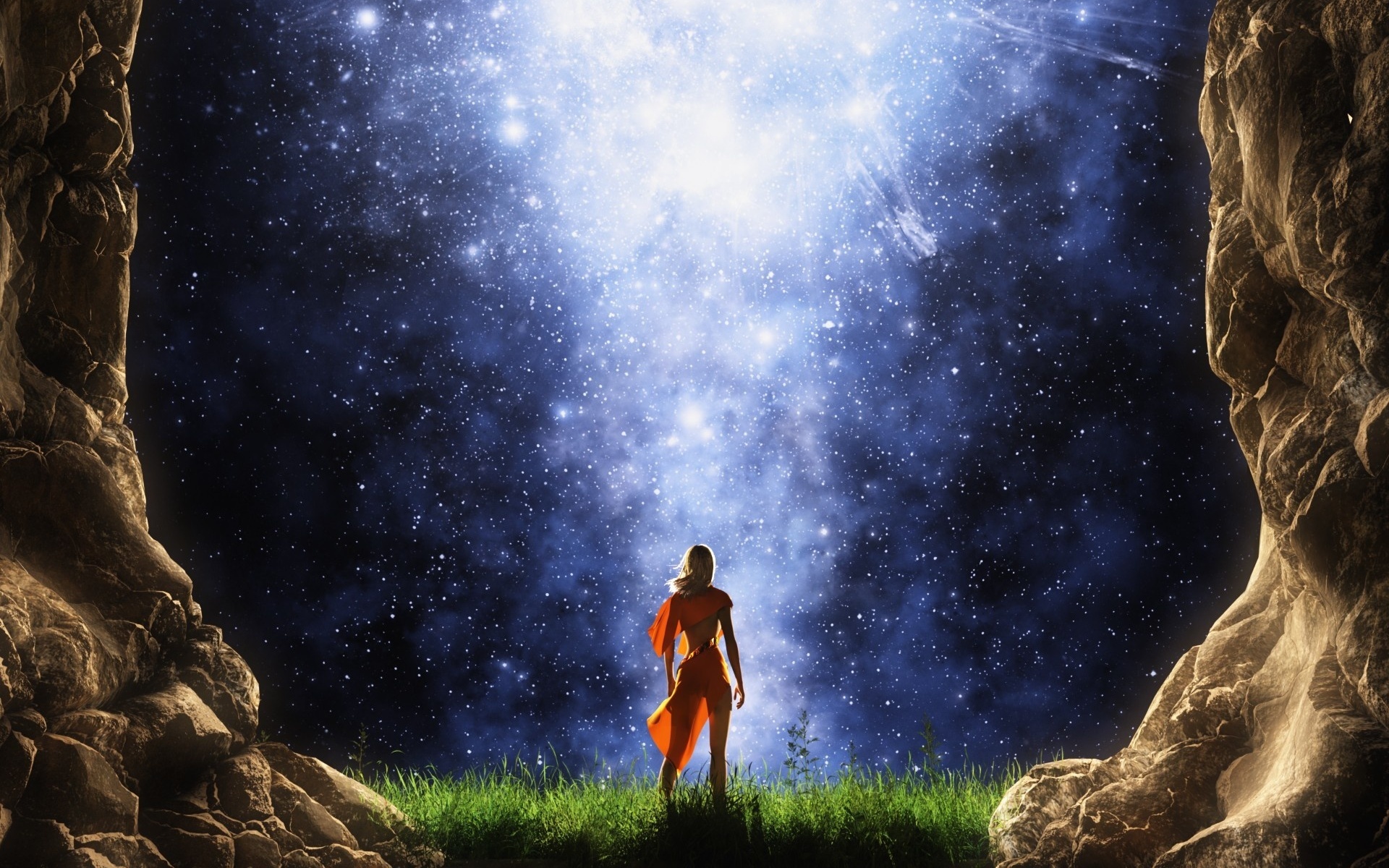 Светловолосая, стройная девушка в оранжевом платье, стоящая на зеленой траве между скалами любуется звездным, ночным небом и Млечном пути