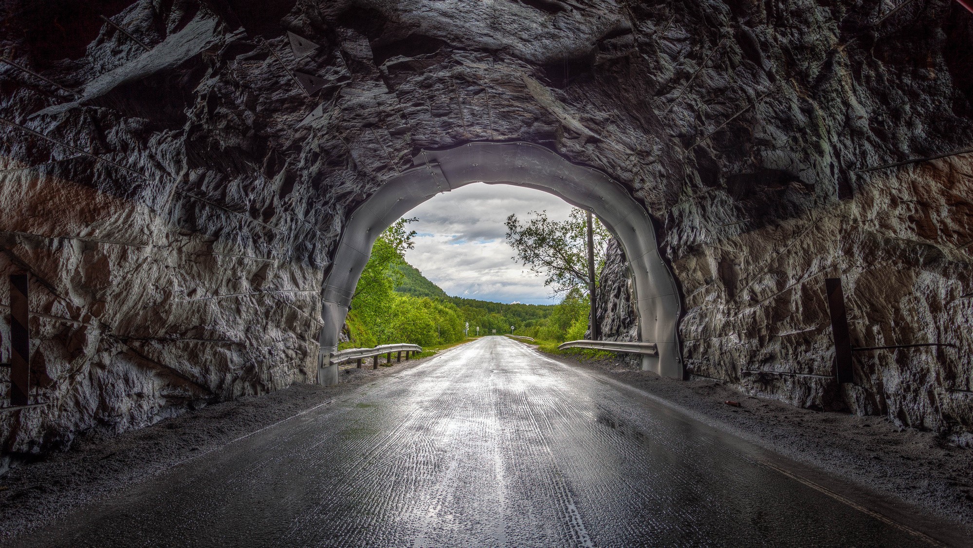 Туннель, уходящая вдаль. дорога после дождя, между холмов и деревьев. под хмурым небом