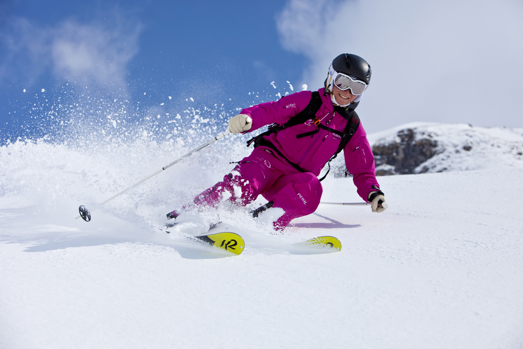 Девушка - лыжница в розовом костюме катается по заснеженному склону