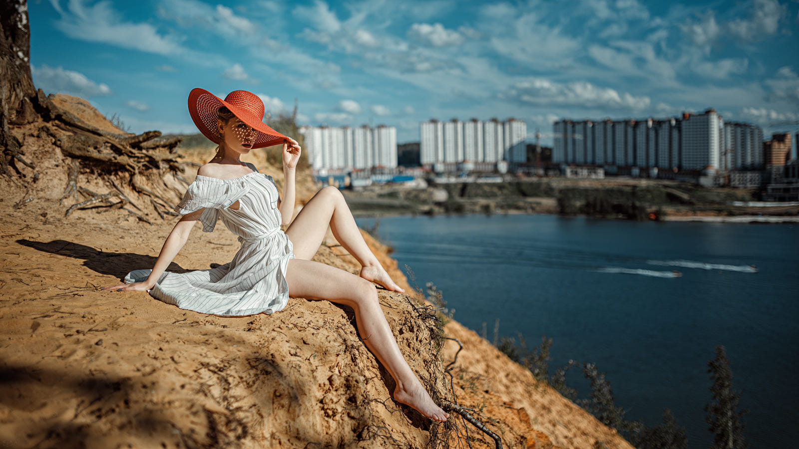 Модель Ксения в шляпе и белом платье сидит на фоне города, фотограф Георгий Чернядьев