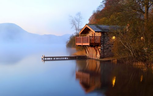 Осень. В рассветной дымке тумана еле видны очертания гор, а вплотную к озеру подступает каменный дом с причалом для лодок