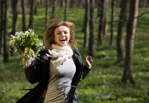 Счастливая радостная девушка, бегущая по лесу с букетом весенних подснежников