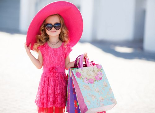 Девочка в красной одежде, в солнцезащитных очках, в огромной красной шляпе, с сумочками в руках после шопинга