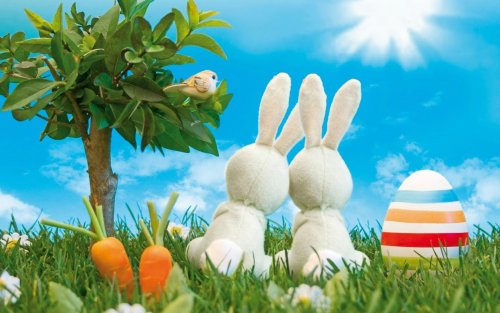Два зайчика под солнышком наблюдают за певчей птичкой, рядом пасхальное яйцо и морковка