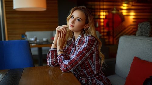 Девушка в клетчатой рубашке сидит за столом