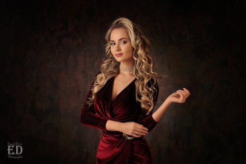 Модель Katya Khalpert / Катя Халперт позирует стоя в бордовом бархатном платье, на фоне темной стены