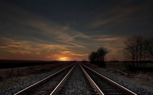 Железнодорожное полотно на фоне пасмурного неба и заходящего солнца