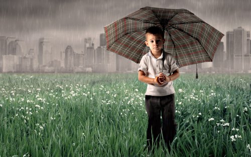 Мальчик с зонтиком на краю города под ливнем