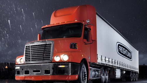 Оранжевый грузовик Freightliner стоит ночью на трассе