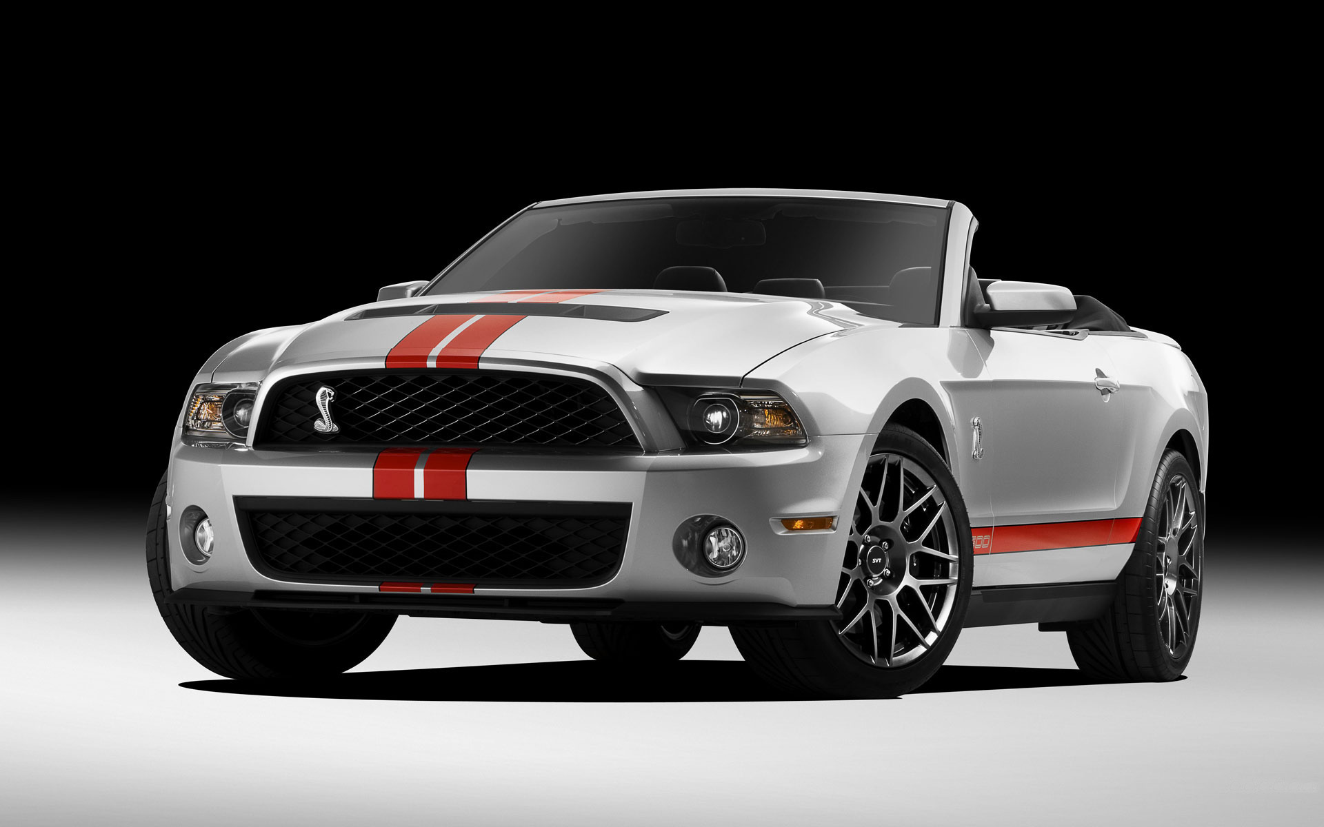 Серебристый Mustang Shelby GT500 модели 2011 года стоит на белой поверхности