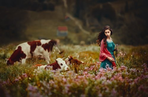 Девушка с длинными волосами стоит на поле, где пасутся коровы, фотограф Monica Lazar