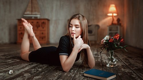 Модель Василиса Саровская в черном платье лежит на полу перед книгой и цветами в вазе, фотограф Георгий Чернядьев
