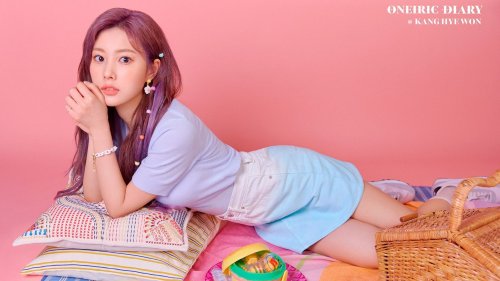Kang Hye Won из АйЗВАН / IZONE позирует, лежа на животе и опираясь на локти, в светло-фиолетовой футболке и градиентных шортах
