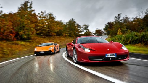 Красный Феррари / Ferrari и оранжевый Ламборгини / Lamborghini едут по мокрой извилистой дороге