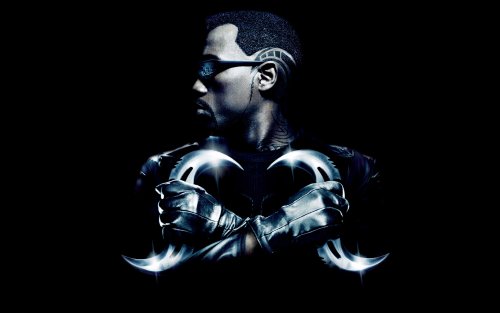 Wesley Snipes из фильма Блэйд / Blade в темных очках и кожаном костюме скрестил руки, держащие два изогнутых клинка
