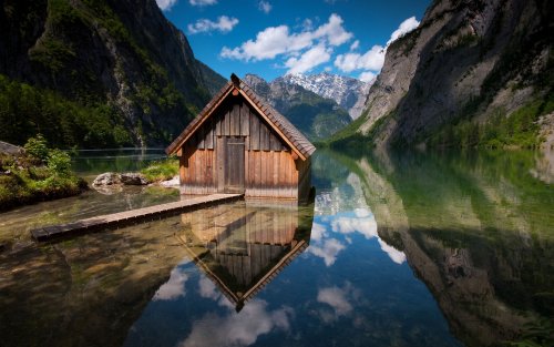 Деревянный домик на озере среди высоких гор