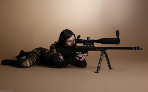 Девушка брюнетка снайпер в камуфляже с винтовкой Barrett M99 в студии